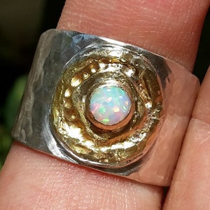 May include: A silver ring with a hammered texture and a gold circle with a white opal gemstone in the center.