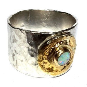 May include: A silver ring with a hammered texture and a gold setting with an opal gemstone.