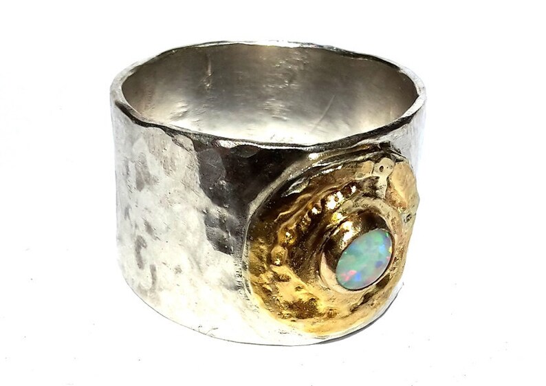 May include: A silver ring with a hammered texture and a gold setting with an opal gemstone.