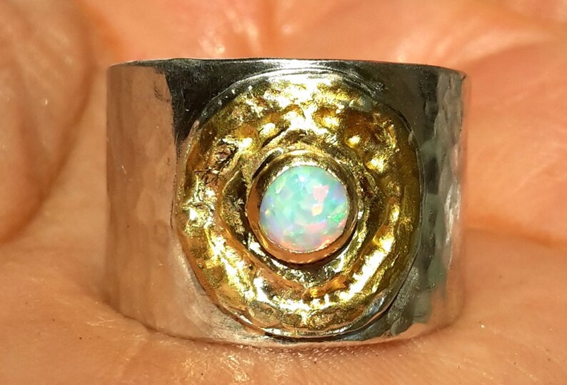 May include: A silver ring with a hammered texture and a gold circle with an opal gemstone in the center.