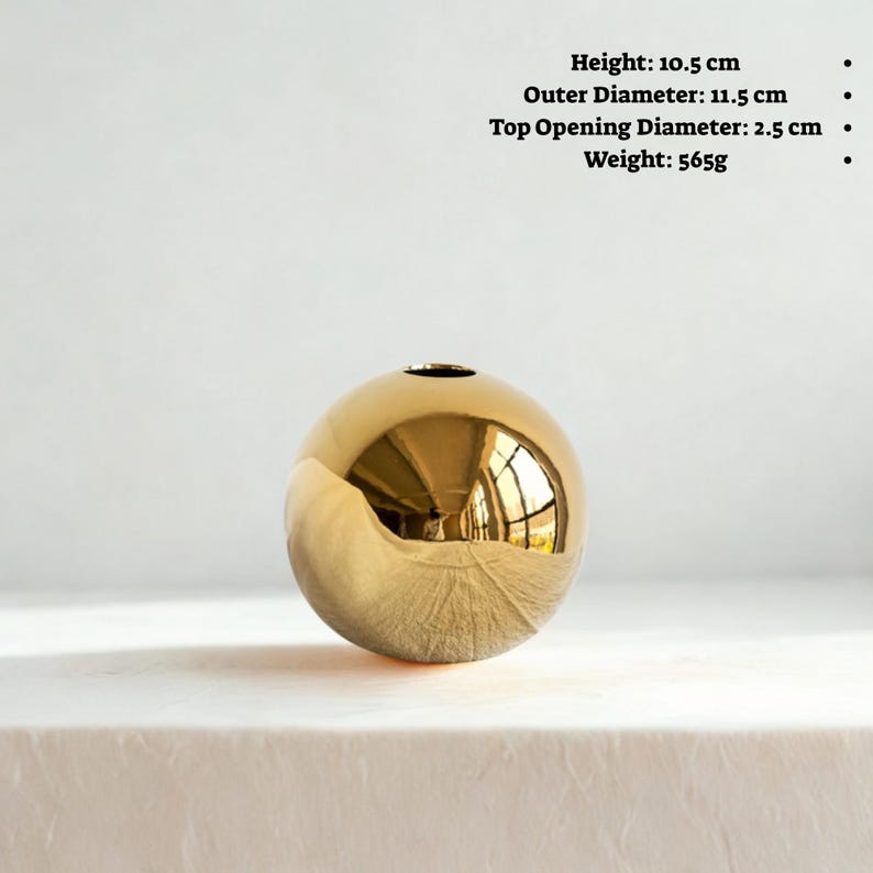 May include: A gold-colored spherical vase with a small opening at the top. The vase is 10.5 cm high, with an outer diameter of 11.5 cm, and a top opening diameter of 2.5 cm. It weighs 565g. The surface reflects the surrounding environment. Home decor.