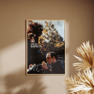 Op de afbeelding: Een filmposter voor de film "The Usual Suspects" met een man in een donker jack die een sigaret aansteekt. De poster heeft een achtergrond van bomen en een auto.
