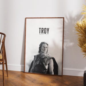 Könnte beinhalten: Ein Schwarzweiß-Poster mit einem Foto von Brad Pitt als Achilles aus dem Film Troy. Das Poster trägt den Titel "Troy" und darunter steht der Text "Brad Pitt".