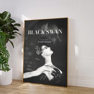 May include: A framed poster for the movie "Black Swan" featuring Natalie Portman. The black and white image shows Portman in a ballet pose with the movie title and her name in white text. The frame is gold.