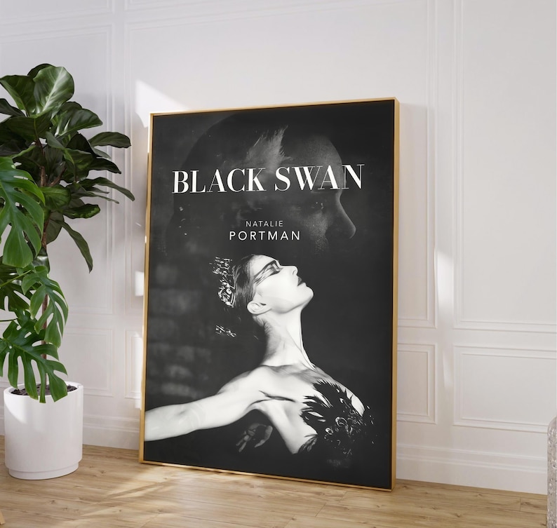 May include: A framed poster for the movie "Black Swan" featuring Natalie Portman. The black and white image shows Portman in a ballet pose with the movie title and her name in white text. The frame is gold.