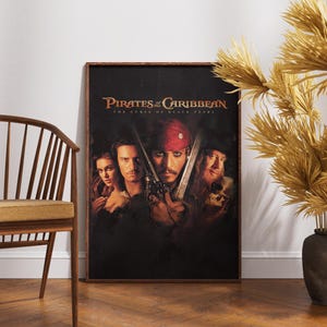 Puede incluir: Póster enmarcado de la película "Piratas del Caribe: La maldición de la Perla Negra". El póster muestra el título de la película y un grupo de actores, incluido Johnny Depp, sobre un fondo oscuro. El póster está sobre un suelo de madera.