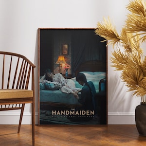 Może przedstawiać: Oprawiony plakat z tytułem "The Handmaiden". Obraz przedstawia dwie kobiety w słabo oświetlonym pokoju z łóżkiem i lampą. Drewniane krzesło i dekoracyjny wazon znajdują się na pierwszym planie.
