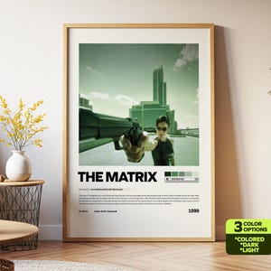 May include: A framed movie poster for "The Matrix" featuring a woman holding a gun, with a cityscape backdrop. The poster has a green and white color scheme, with the movie title prominently displayed. The poster includes the year 1999.