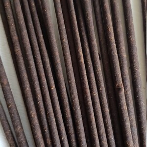 May include: A bundle of brown incense sticks, arranged in a fan shape. The sticks are about 10 inches long and have a rough, textured surface.