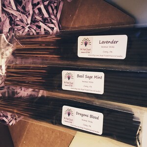May include: Three packages of incense sticks in clear plastic packaging. The packages are stacked on top of each other. The top package is labeled "Lavender Incense Sticks". The middle package is labeled "Basil Sage Mint Incense Sticks". The bottom package is labeled "Dragon's Blood Incense Sticks".