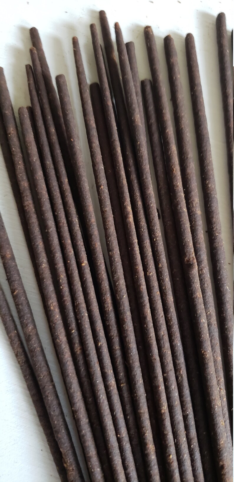 May include: A bundle of brown incense sticks, arranged in a fan shape. The sticks are approximately 25 cm long and have a rough, textured surface.