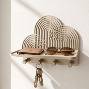 Könnte beinhalten: Beiges Wandregal mit Bogen-Design, das ein braunes Portemonnaie, eine Sonnenbrille und Schlüssel enthält. Das Regal hat vier Haken zum Aufhängen von Gegenständen. Das Design ist minimalistisch und modern.
