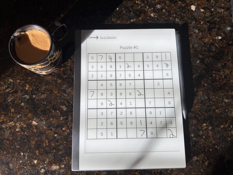 May include: A white sheet of paper with a Sudoku puzzle printed on it. The puzzle is labeled "Puzzle #1" and has numbers 1 through 9 filled in some of the squares. The puzzle is partially solved with some numbers filled in.