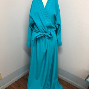 May include: A long, turquoise blue robe with a shawl collar and a tie belt. The robe has a straight, flowing silhouette and is made of a soft, comfortable fabric.