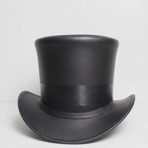 May include: A solid black top hat with a smooth, matte finish and a structured cylindrical crown. The hat features a wide, curved brim and a matching black satin ribbon band wrapped around the base of the crown, creating a uniform appearance.