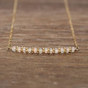 May include: A delicate gold chain necklace with a row of small white opal beads.