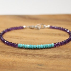 May include: A delicate bracelet with a row of turquoise beads and amethyst beads on either side. The bracelet is made with sterling silver.