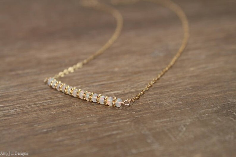 May include: A delicate gold chain necklace with a row of small white opal beads.