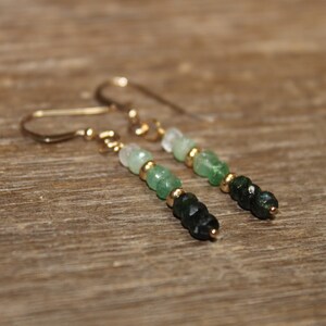 May include: A pair of gold dangle earrings featuring green and white gemstone beads. The beads are graduated in size, with the largest beads at the bottom of the earrings.