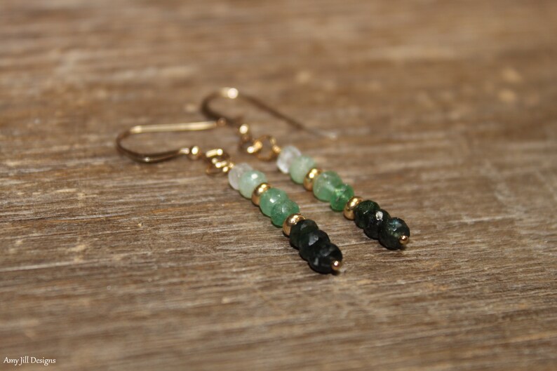 May include: A pair of gold dangle earrings featuring green and white gemstone beads. The beads are graduated in size, with the largest beads at the bottom of the earrings.