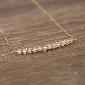 May include: A delicate gold chain necklace with a row of small white opal beads.