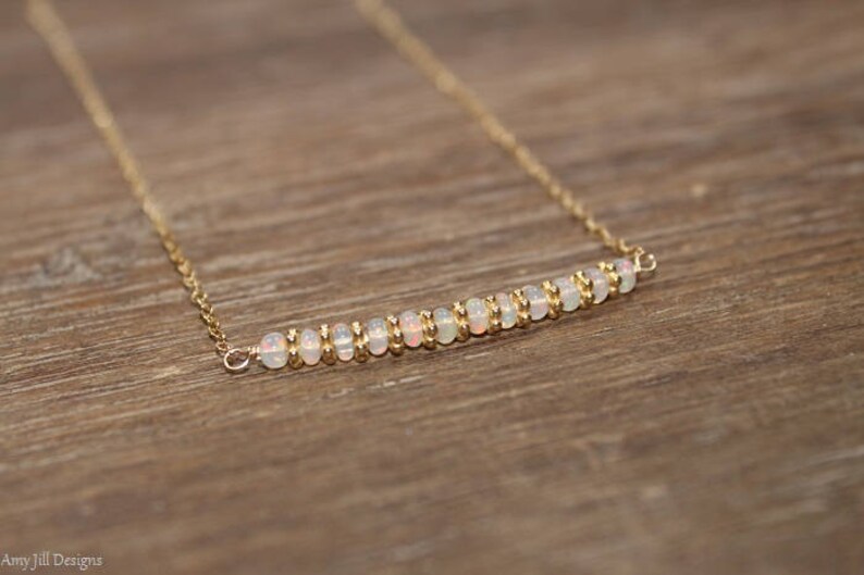 May include: A delicate gold chain necklace with a row of small white opal beads.