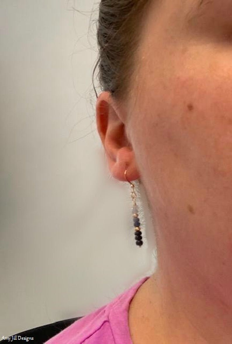 May include: A pair of dangle earrings with a gold hook and a chain with blue and black beads.
