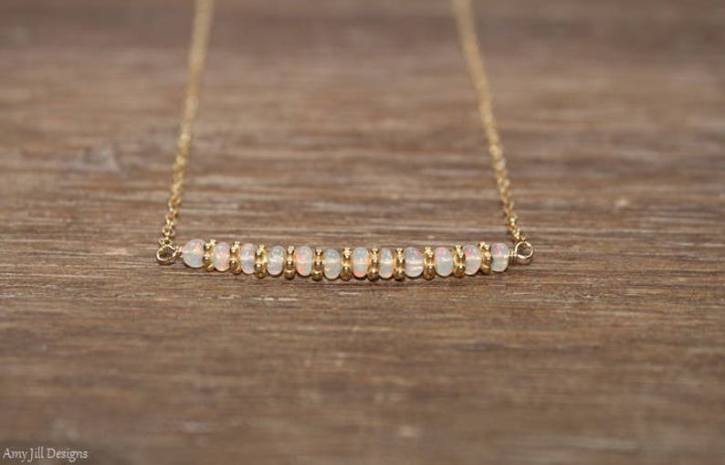 May include: A delicate gold chain necklace with a row of small white opal beads.