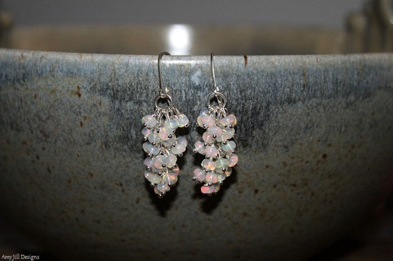 Peut inclure: Une paire de boucles d'oreilles en argent avec un groupe de pierres d'opale blanches suspendues &agrave; chaque boucle d'oreille.