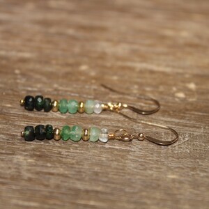May include: A pair of gold earrings featuring a gradient of green gemstone beads. The beads range from dark green to light green.