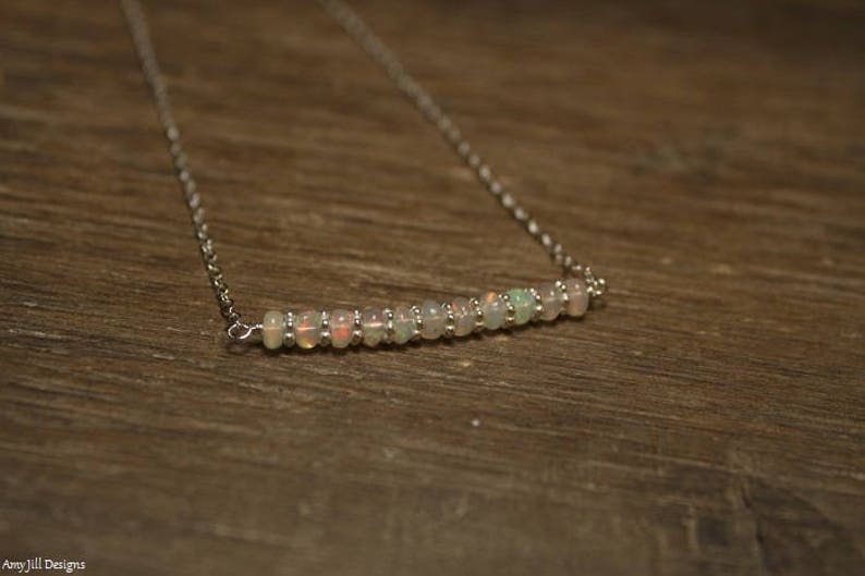 May include: A silver chain necklace with a row of small, iridescent opal beads.
