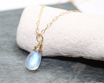 May include: A delicate gold chain necklace with a teardrop-shaped moonstone pendant wrapped in gold wire.