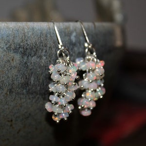 Peut inclure: Une paire de boucles d'oreilles en argent avec un groupe d'opales blanches suspendues &agrave; chaque boucle d'oreille.