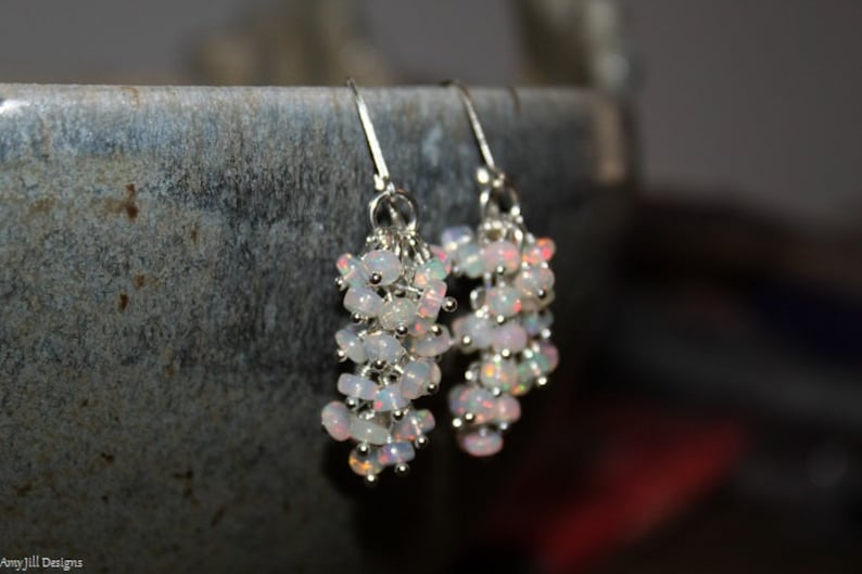 Peut inclure: Une paire de boucles d'oreilles en argent avec un groupe d'opales blanches suspendues &agrave; chaque boucle d'oreille.