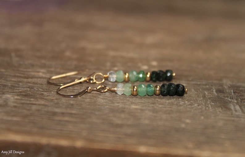 May include: A pair of gold dangle earrings with a gradient of green and black gemstone beads.