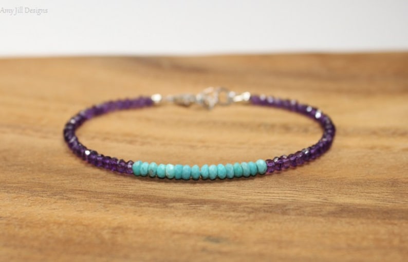 May include: A delicate bracelet with a row of turquoise beads and amethyst beads on either side. The bracelet is made with sterling silver.