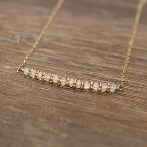 May include: A gold chain necklace with a bar of white opal beads.