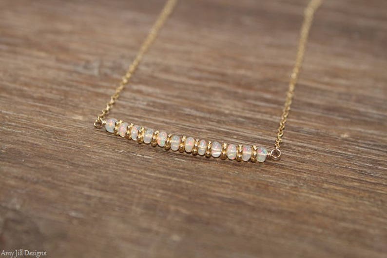 May include: A gold chain necklace with a bar of white opal beads.