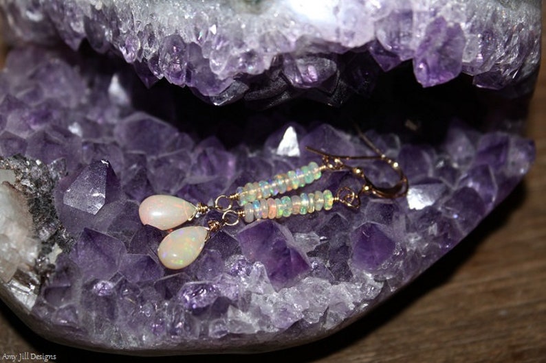 Puede incluir: Pendientes dorados con colgantes de &oacute;palo en forma de l&aacute;grima y detalles de cuentas. Los pendientes se exhiben sobre una geoda de amatista p&uacute;rpura. La joyer&iacute;a tiene un dise&ntilde;o delicado y es adecuada para el uso diario o ocasiones especiales.