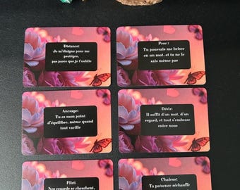 May include: An assortment of items including a heart-shaped candle, a polished stone, and six cards with text and floral designs. The cards feature phrases like "Distance" and "Desire". A decorative pendant hangs in the upper left corner.