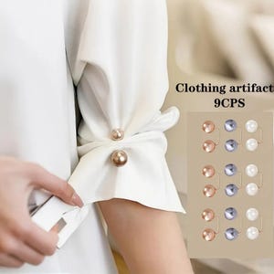 Puede incluir: Una manga de prenda blanca ajustada con un alfiler de metal dorado que presenta dos perlas esféricas. La imagen incluye una muestra de nueve accesorios de ropa en tres colores: dorado metálico, gris y blanco.