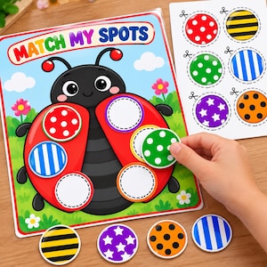 Puede incluir: Un juego educativo Match My Spots con una mariquita de dibujos animados sobre un campo verde y cielo azul. El juego incluye piezas circulares con varios patrones como lunares, rayas y estrellas para colocar en las alas de la mariquita.