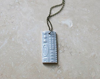 Stunning vintage 70's ice blue gloss cypher drop pendant with long antique brass chain.