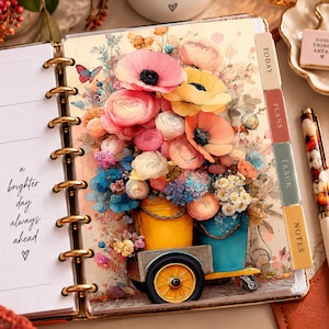 May include: A spiral-bound planner featuring a floral illustration of pink, yellow, and orange flowers in a yellow cart and blue bucket. The left page displays the text 'a brighter day always ahead' with a heart. Four tabs labeled TODAY, PLANS, TRACK, and NOTES are visible.
