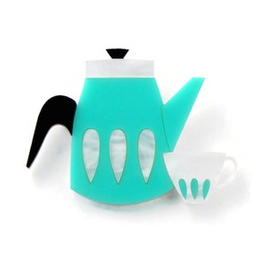 May include: A turquoise teapot and a white teacup with turquoise accents. The teapot has a black handle and a white lid. Both pieces have a retro design.