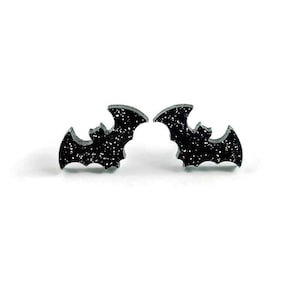May include: A pair of black glitter bat stud earrings. The earrings are small and delicate, and they would be perfect for a Halloween party or any other occasion.