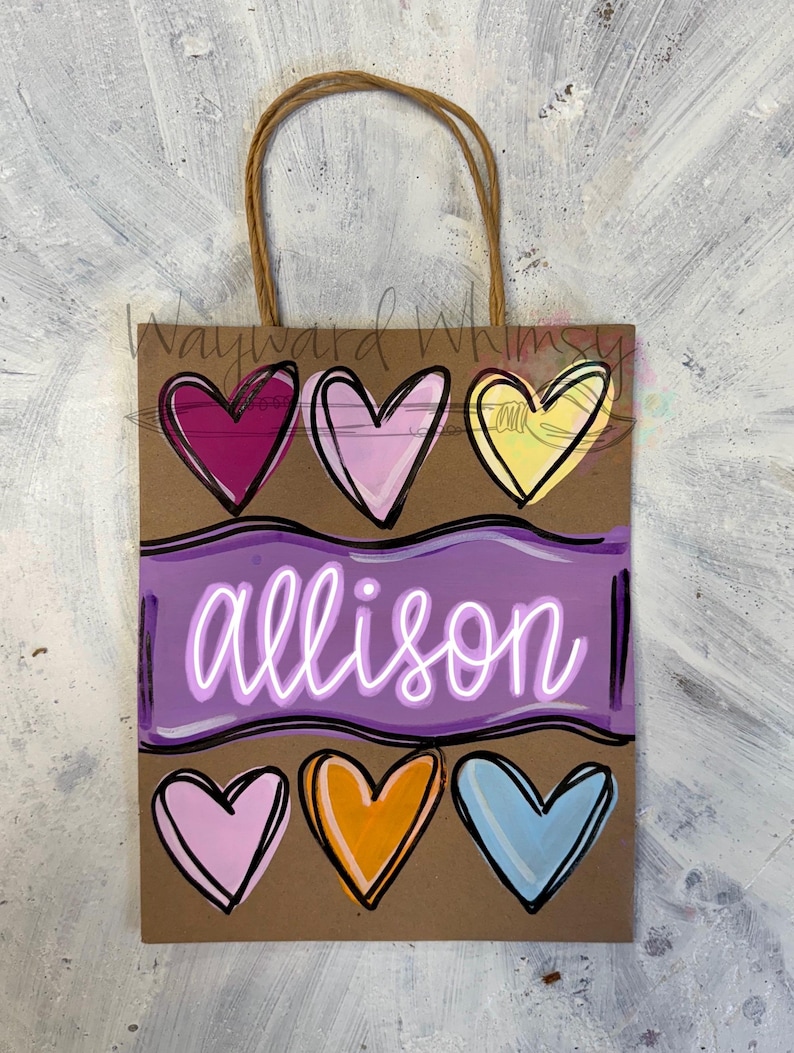 May include: A brown paper gift bag with a jute handle. The bag features a purple banner with the name "allison" in white script, and six colorful hearts in shades of pink, yellow, orange, and blue.