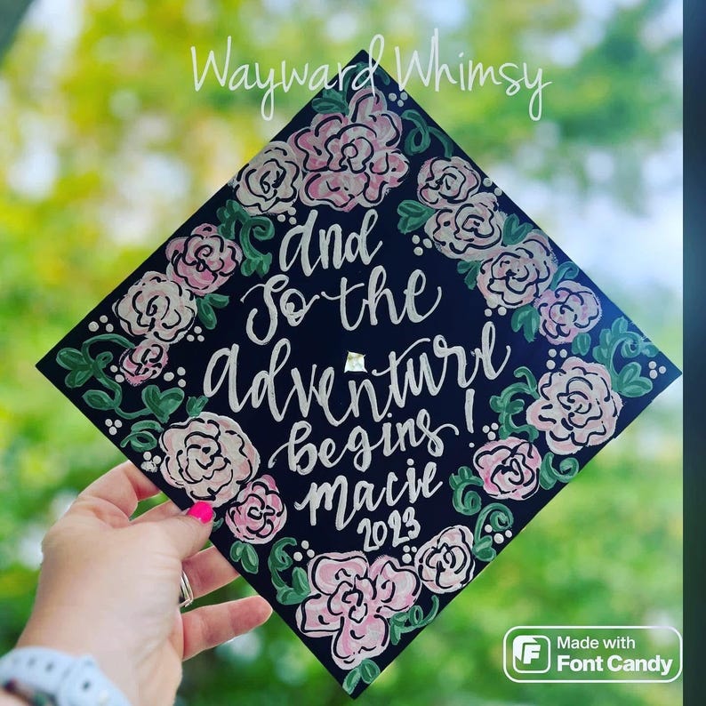 May include: Black graduation cap decorated with pink and green flowers and the text "And so the adventure begins! Macie 2023".