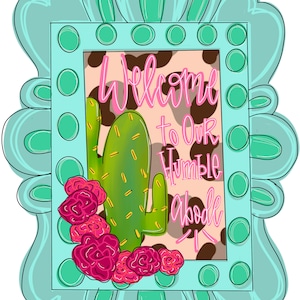 May include: A turquoise frame with a cow print background and a cactus. The text "Welcome to our Humble Abode" is written in pink.