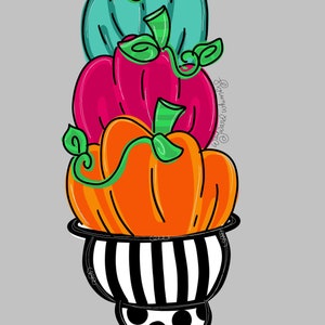 Puede incluir: Una pila de tres calabazas en una maceta de rayas blancas y negras con lunares. Las calabazas son naranja, rosa y turquesa.
